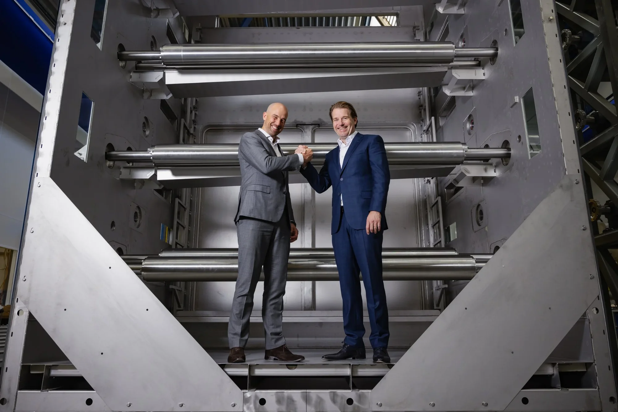 Representatives of Battolyser Systems and VDL Hydrogen Systems shaking hands in front of an electrolyser stack